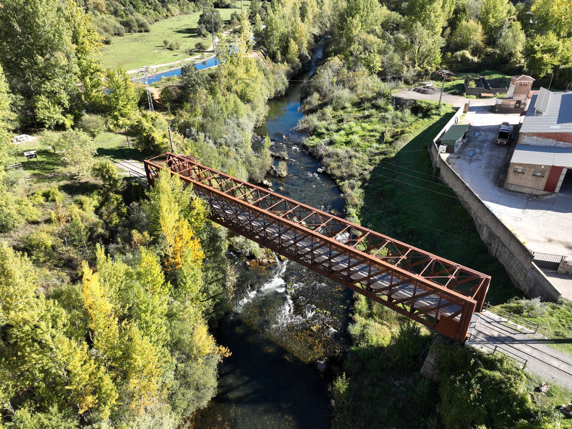 Puente metálico completo y río desde arriba en diagonal; se aprecian los dos accesos.