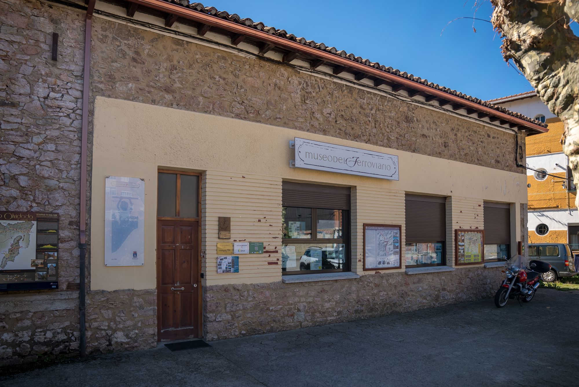 Fachada amplia del museo, puerta, rótulo y tres ventanas, con moto a la derecha.